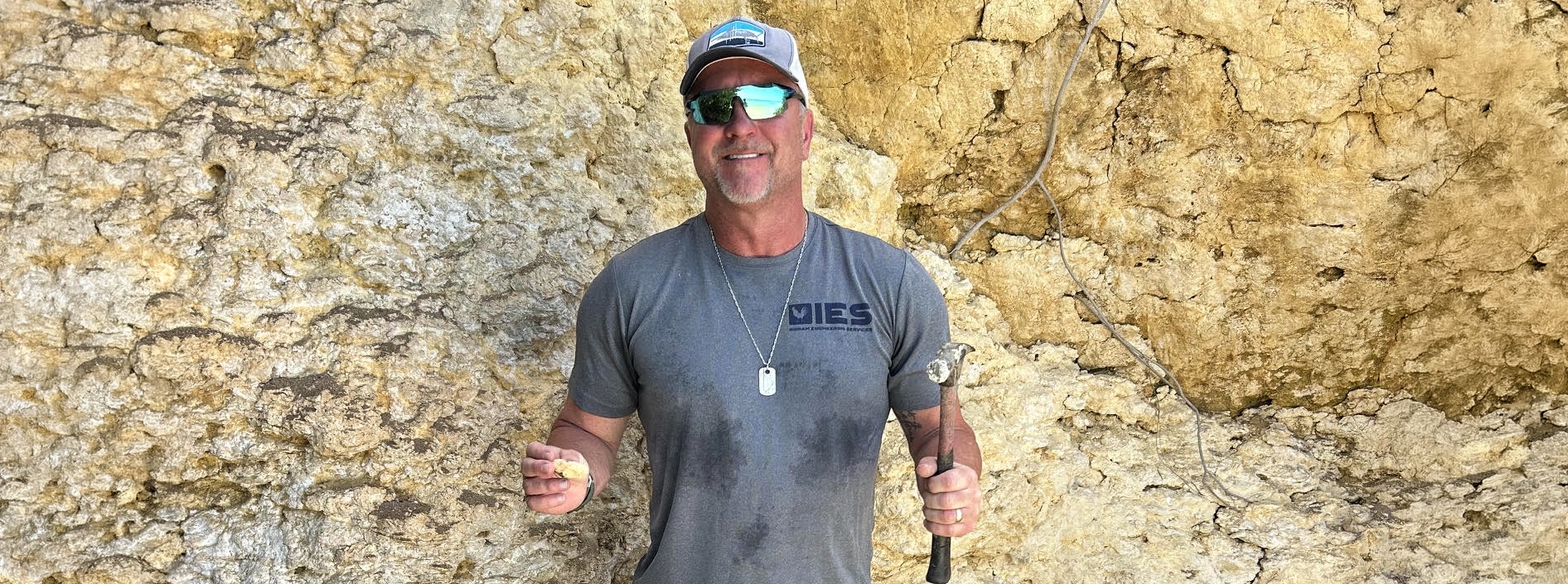 Chadd Ingram, P.E. inspecting eroded limestone cliff with hammer and rock sample at Caribbean resort