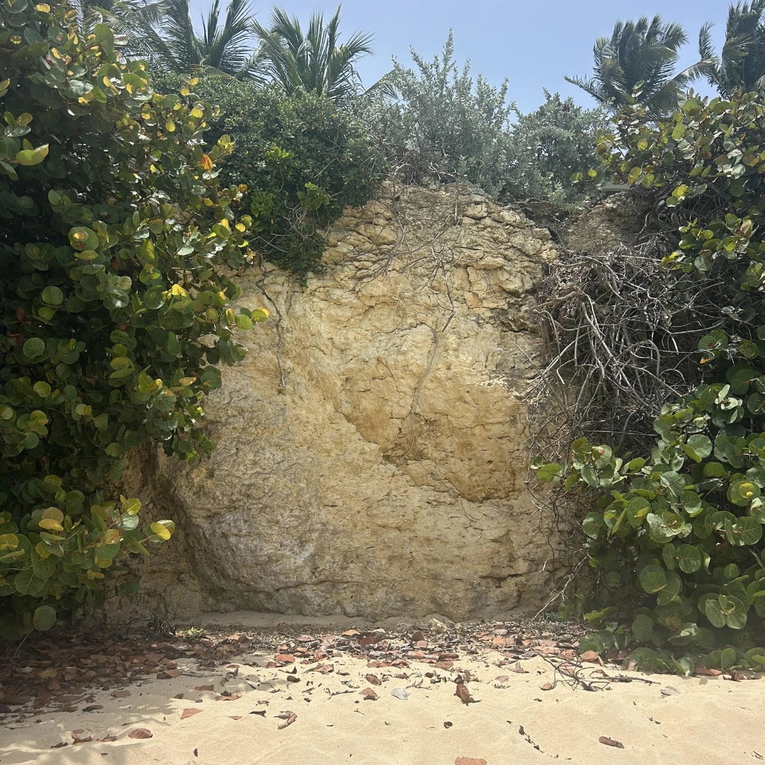 Eroded limestone cliff face beneath coastal resort villas