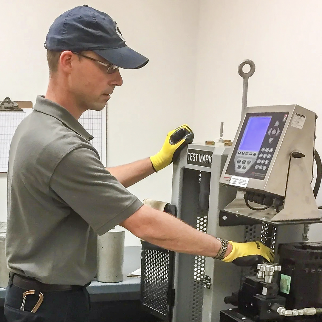 Laboratory technician operating a concrete compression testing machine at Ingram Engineering’s materials testing laboratory in West Chester, PA.